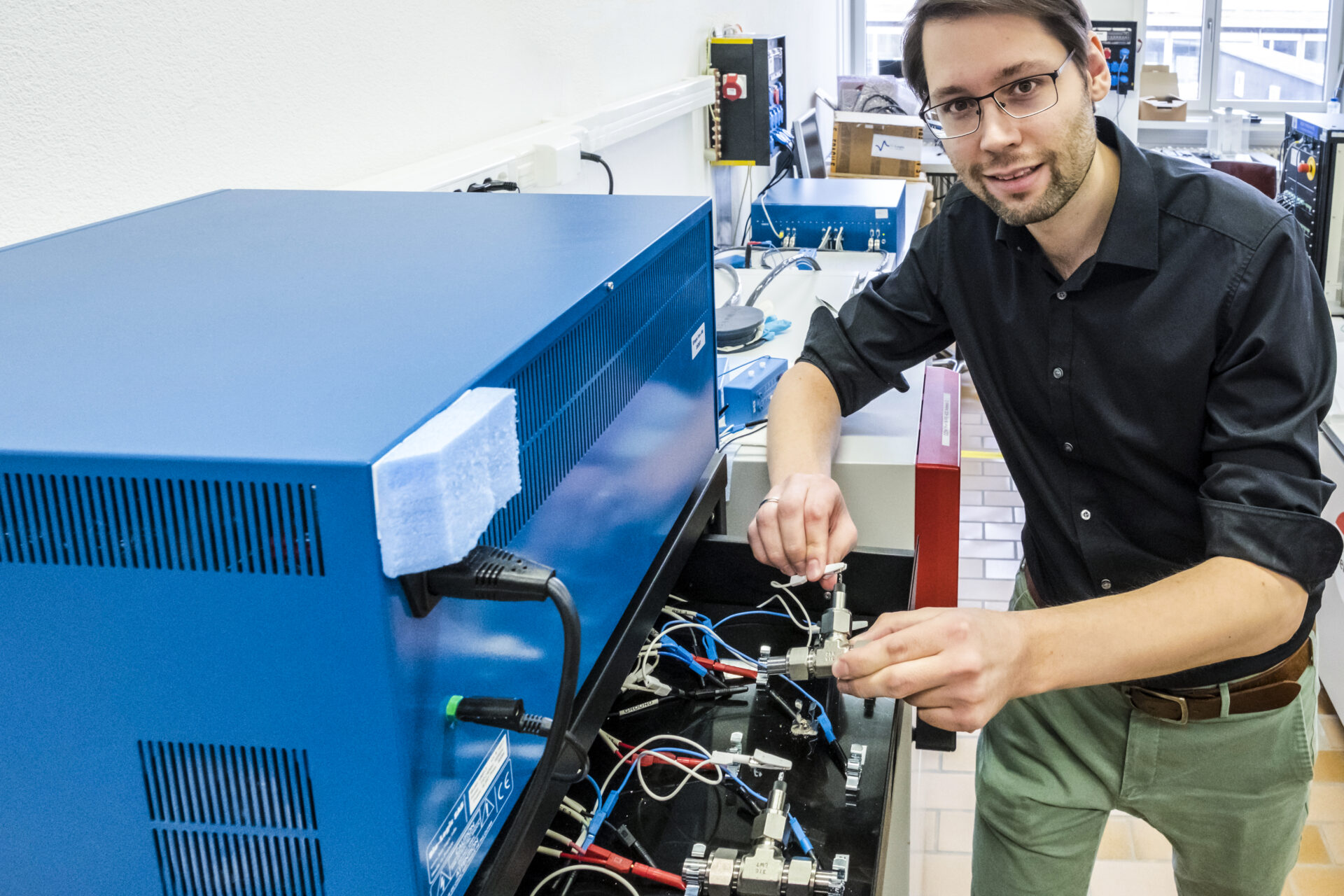 Forschung am Wasser-Elektrolyt: Empa-Forscher Ruben-Simon Kühnel schliesst eine Test-Zelle mit der konzentrierten Salzlösung ans Ladegerät an. In mehreren Lade- und Endladezyklen wird die Stabilität des Systems ermittelt. Bild: Empa