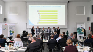 Mehrere Fachleute diskutieren beim Nachhaltigkeitsforum von Vinyl Plus Deutschland in Bonn auf einer Bühne vor Publikum über Klimaneutralität in der PVC-Branche.