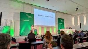 Blick in den Konferenzsaal der bvse-Jahrestagung 2025 mit Verbandspräsident Henry Forster am Podium und Teilnehmenden im Publikum.