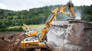 Zwei gelbe Liebherr-Bagger beim kontrollierten Abbruch der Zeller Brücke im Odenwald, die mit Hydraulikhämmern die Brückenteile zerkleinern.